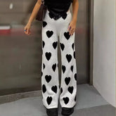 Person wearing white pants with black heart patterns in an indoor setting